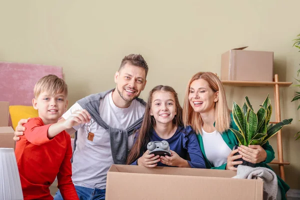 Família feliz com pertences e chaves em sua nova casa — Fotografia de Stock