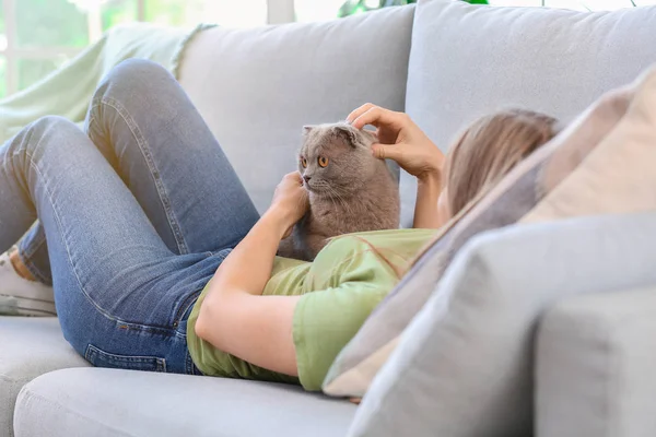 Piękna kobieta z cute kota leżącego na kanapie w domu — Zdjęcie stockowe