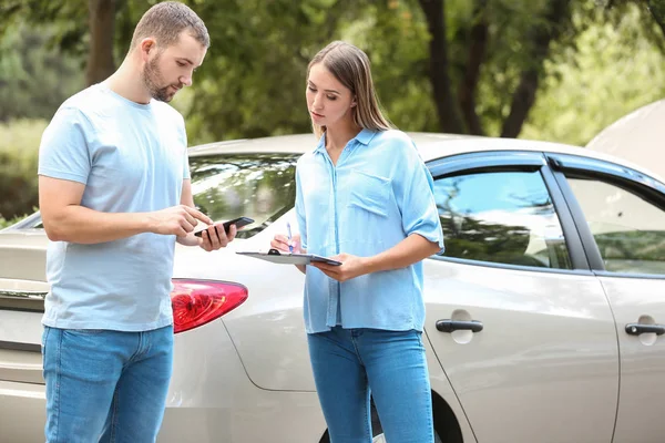 Motorista e agente de seguros perto do carro danificado ao ar livre — Fotografia de Stock