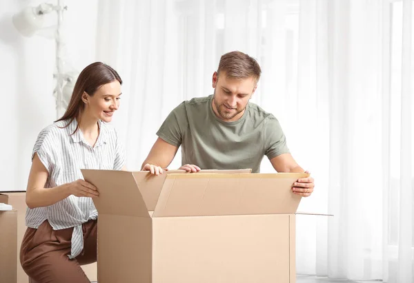 Pareja joven desempacando cosas después de mudarse a casa nueva — Foto de Stock