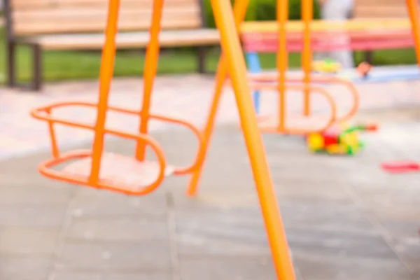 Blurred view of swings on playground in park — Stock Photo, Image