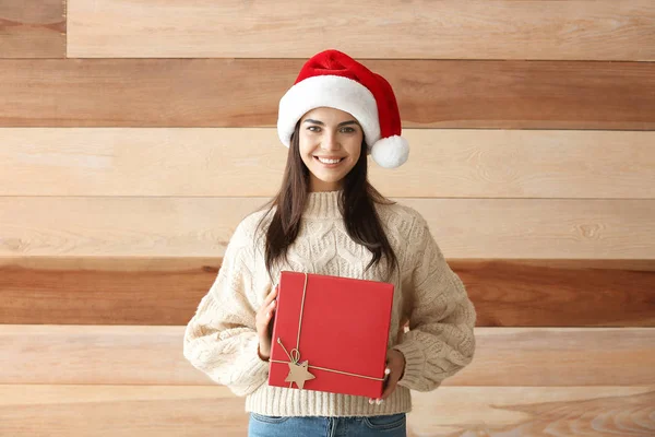 Schöne junge Frau mit Weihnachtsgeschenk auf Holzgrund — Stockfoto