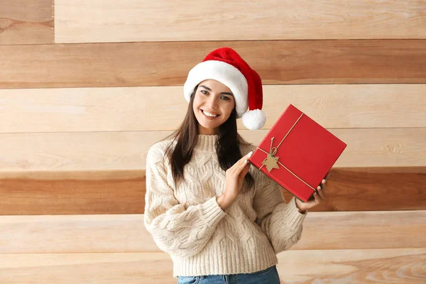 Mulher bonita com presente de Natal no fundo de madeira — Fotografia de Stock