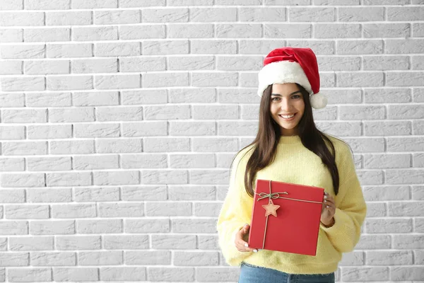 Mulher bonita com presente de Natal contra parede de tijolo — Fotografia de Stock