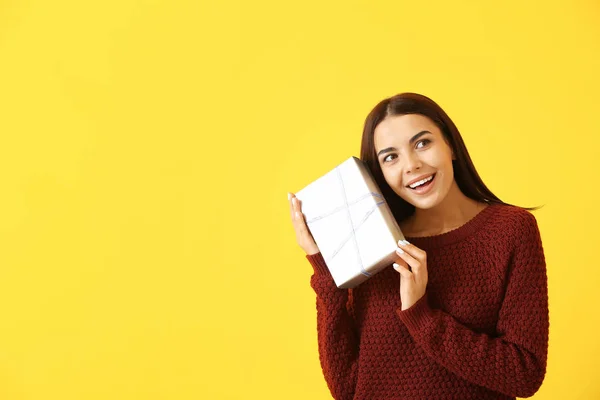 Beautiful young woman with gift on color background — Stock Photo, Image