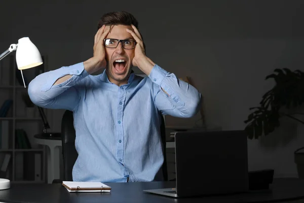 Stressed young man at workplace late in evening — Stock Photo, Image