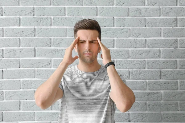 Stressed young man against brick wall — Stock Photo, Image