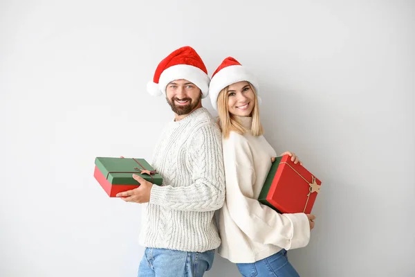 Happy couple with Christmas gifts on light background — Stock Photo, Image
