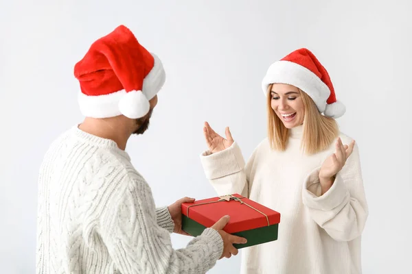 Man giving his wife Christmas present on light background — Stock Photo, Image