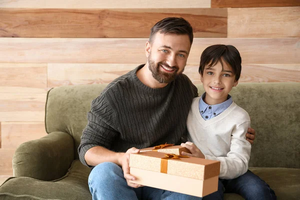 Homem feliz e seu filho com presentes de Natal sentado no sofá — Fotografia de Stock