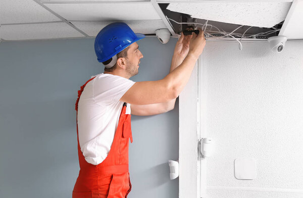 Electrician installing alarm system indoors