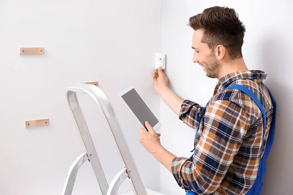 Electricista con tablet ordenador instalando sistema de alarma en interiores — Foto de Stock