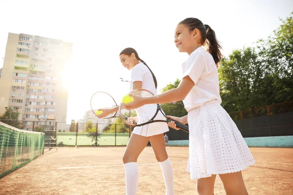 Klein meisje en haar moeder tennissen op het veld — Stockfoto