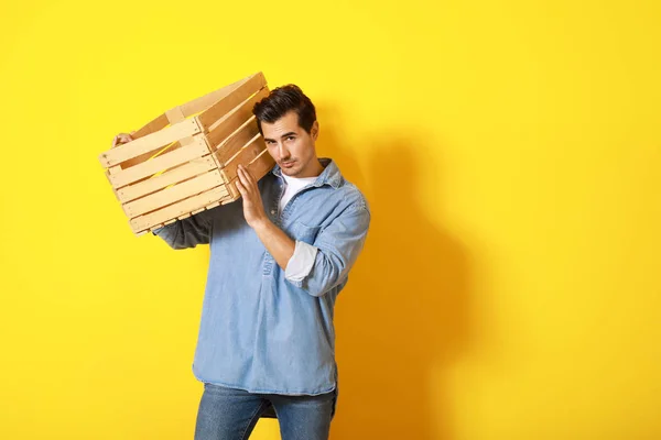 Elegante uomo alla moda con scatola di legno su sfondo di colore — Foto Stock