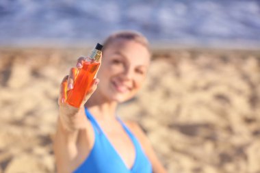 Deniz plajında güneş koruma kremi ile güzel genç kadın