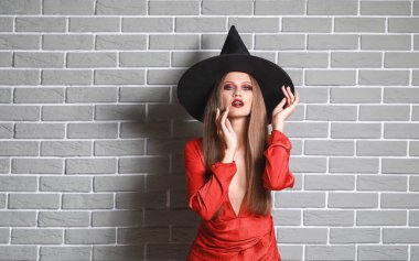 Tuğla duvara karşı Cadılar Bayramı için cadı gibi giyinmiş güzel kadın