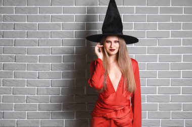 Tuğla duvara karşı Cadılar Bayramı için cadı gibi giyinmiş güzel kadın