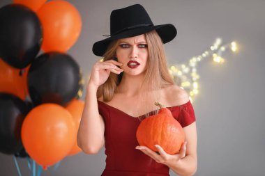 Gri arka planda Cadılar Bayramı için cadı gibi giyinmiş güzel kadın