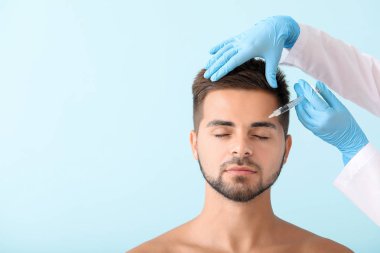 Yakışıklı adam renk arka plan üzerinde dolgu enjeksiyonu alan