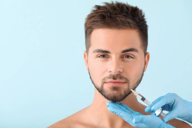 Yakışıklı adam renk arka plan üzerinde dolgu enjeksiyonu alan