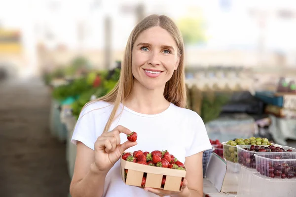 Kobieta ze świeżych truskawek w koszyku na rynku — Zdjęcie stockowe