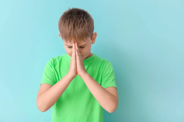 Praying little boy on color background — Stock Photo, Image