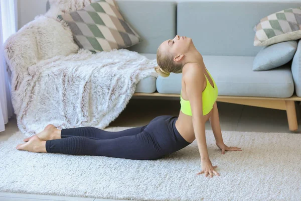 Ung kvinna som utövar yoga hemma — Stockfoto