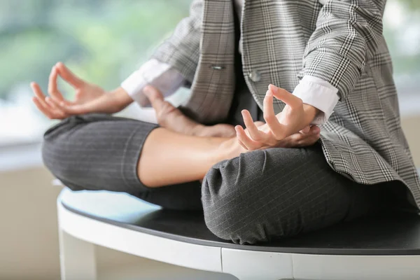 Genç iş kadını ofiste meditasyon yapıyor.