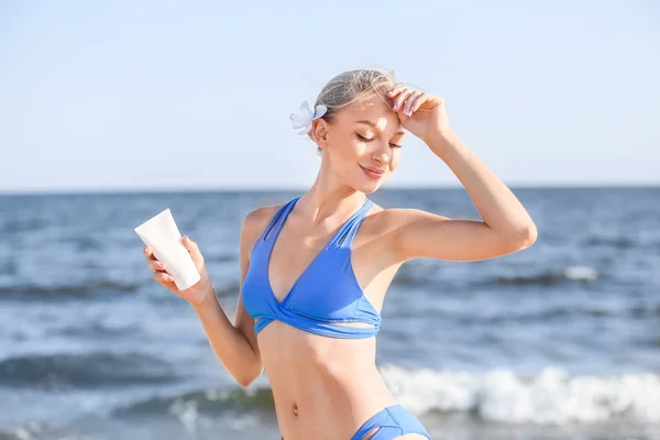 Hermosa mujer joven con crema de protección solar en la playa de mar — Foto de Stock