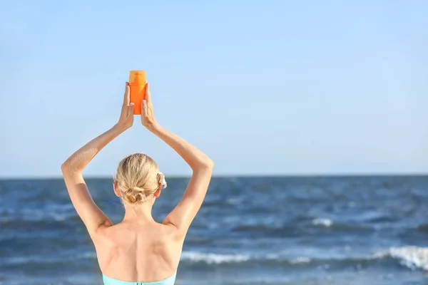 Красива молода жінка з сонцезахисним кремом на морському пляжі — стокове фото