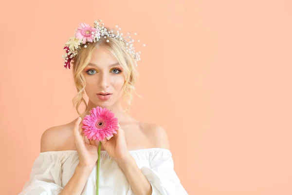 Vacker ung kvinna med blomsterkrans på färgbakgrund — Stockfoto