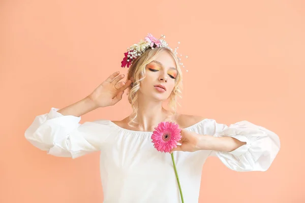 Vacker ung kvinna med blomsterkrans på färgbakgrund — Stockfoto