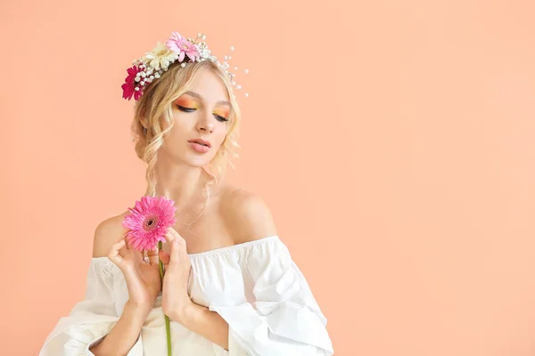 Beautiful young woman with flower wreath on color background — Stock Photo, Image