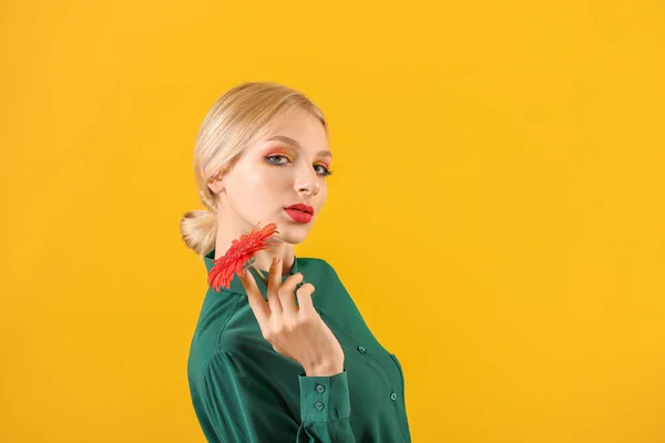 Mooie jonge vrouw met Gerbera bloem op kleur achtergrond — Stockfoto