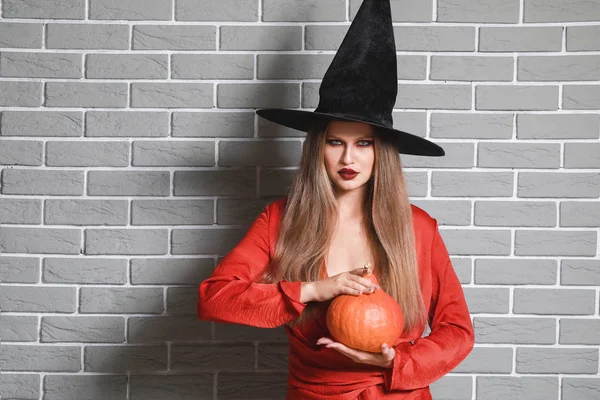 Gyönyörű nő öltözött boszorkány a Halloween ellen téglafal — Stock Fotó
