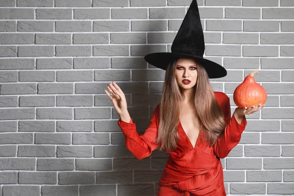 Gyönyörű nő öltözött boszorkány a Halloween ellen téglafal — Stock Fotó