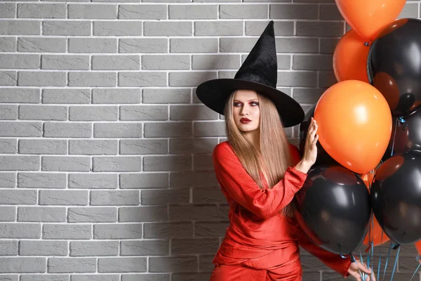 Gyönyörű nő öltözött boszorkány a Halloween ellen téglafal — Stock Fotó