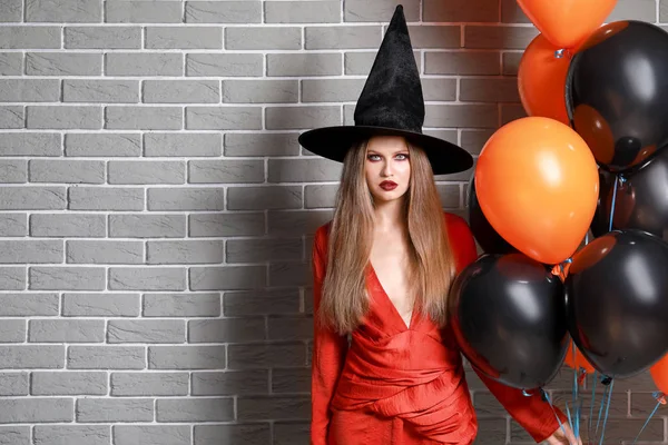 Belle femme habillée en sorcière pour Halloween contre un mur de briques — Photo