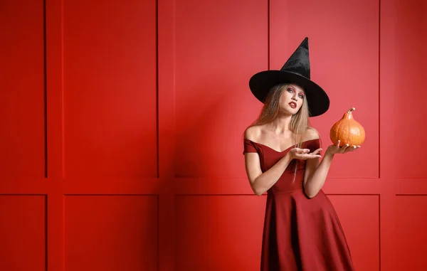 Mooie vrouw verkleed als heks voor Halloween op kleur achtergrond — Stockfoto