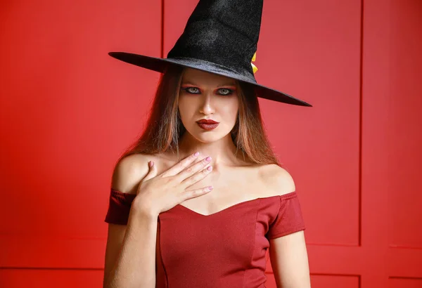 Krásná žena oblečená jako čarodějnice na Halloween na barevném pozadí — Stock fotografie