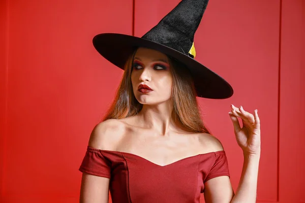 Smuk kvinde klædt som heks til Halloween på farve baggrund - Stock-foto
