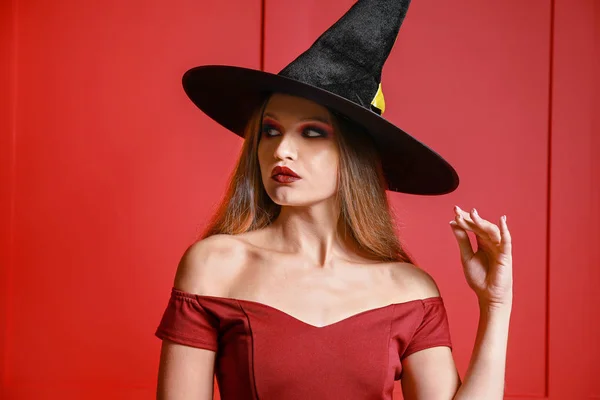 Mooie vrouw verkleed als heks voor Halloween op kleur achtergrond — Stockfoto