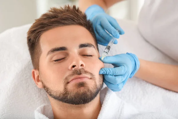 Handsome man receiving filler injection in beauty salon — Stock Photo, Image