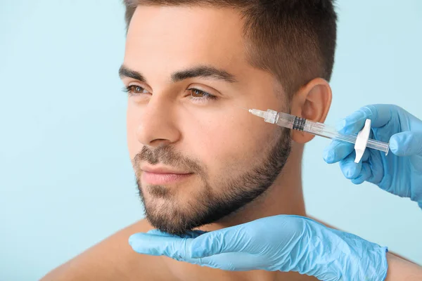 Handsome man receiving filler injection on color background — Stock Photo, Image