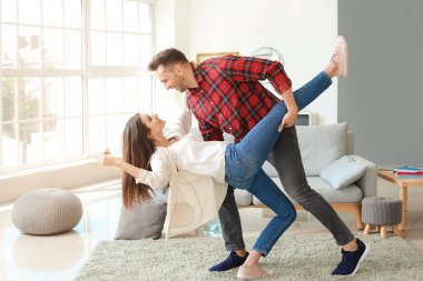 Mutlu genç çift evde dans ediyor.