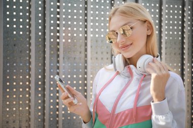 Kulaklık ve cep telefonu açık havada güzel genç kadın
