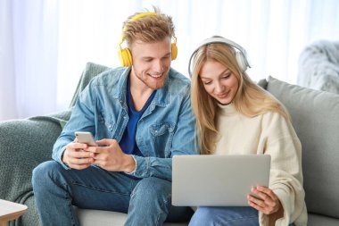 Dizüstü bilgisayar ile genç çift evde müzik dinlerken