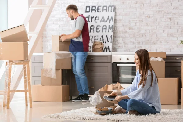 Young couple unpacking things after moving into new house — Stock Photo, Image