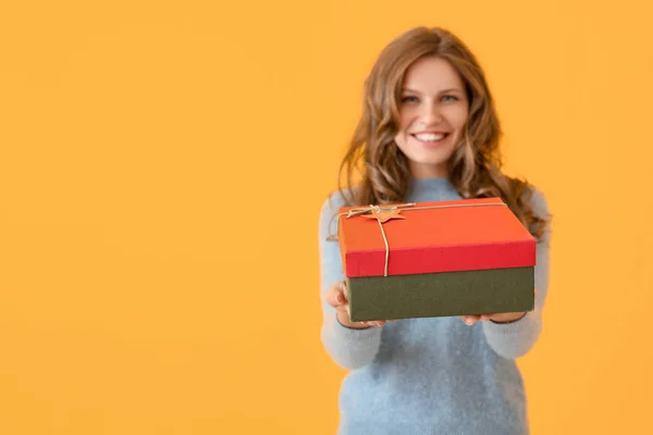 Joyeux jeune femme avec cadeau de Noël sur fond de couleur — Photo