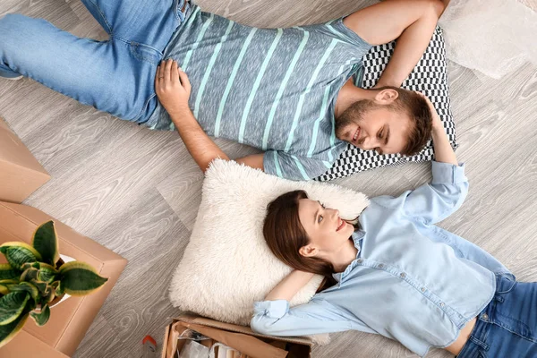 Happy young couple with belongings lying on floor in their new house — Stock Photo, Image